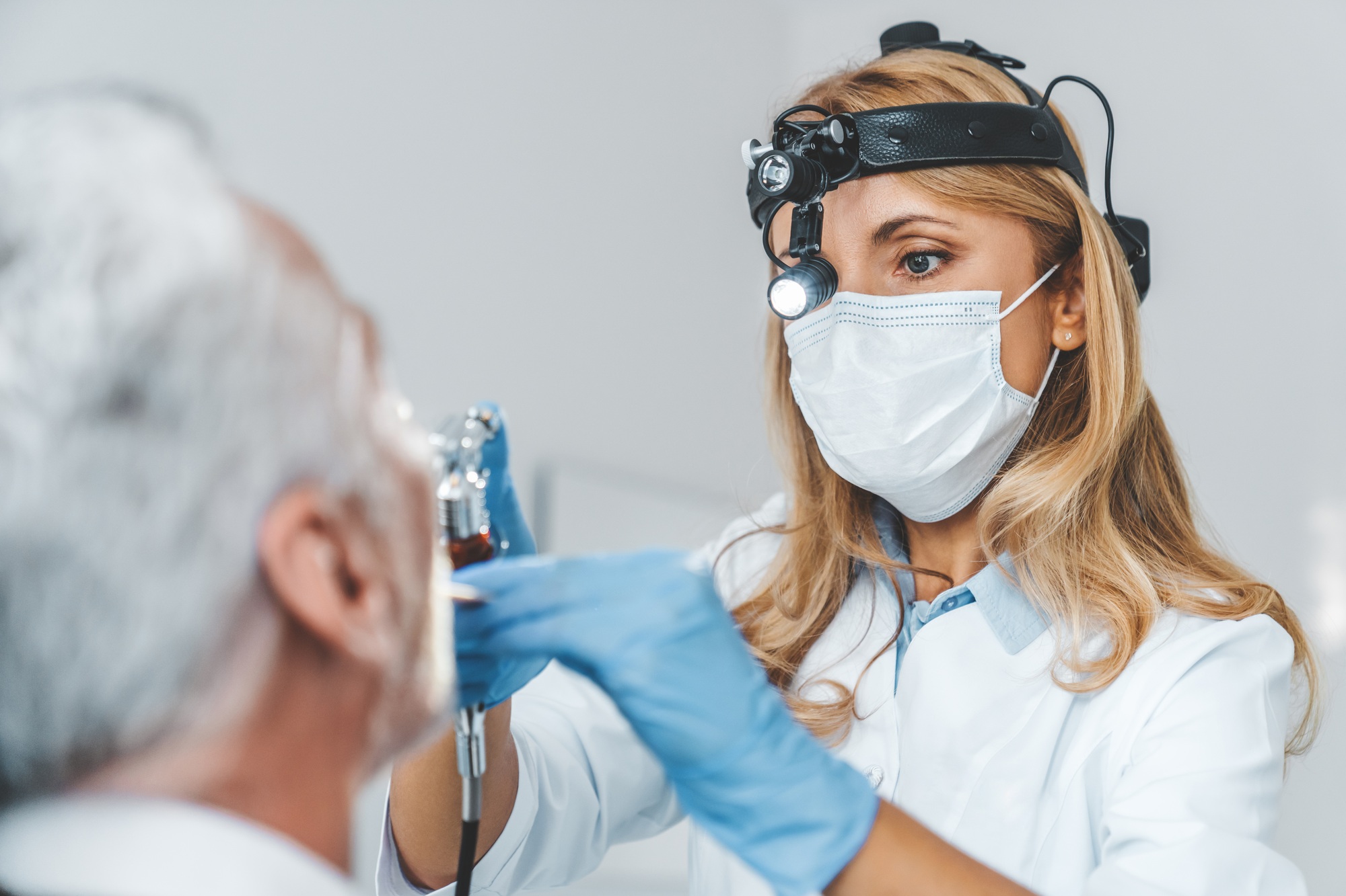 Close up of otolaryngologist making endoscopic examination of oral cavity for senior patient