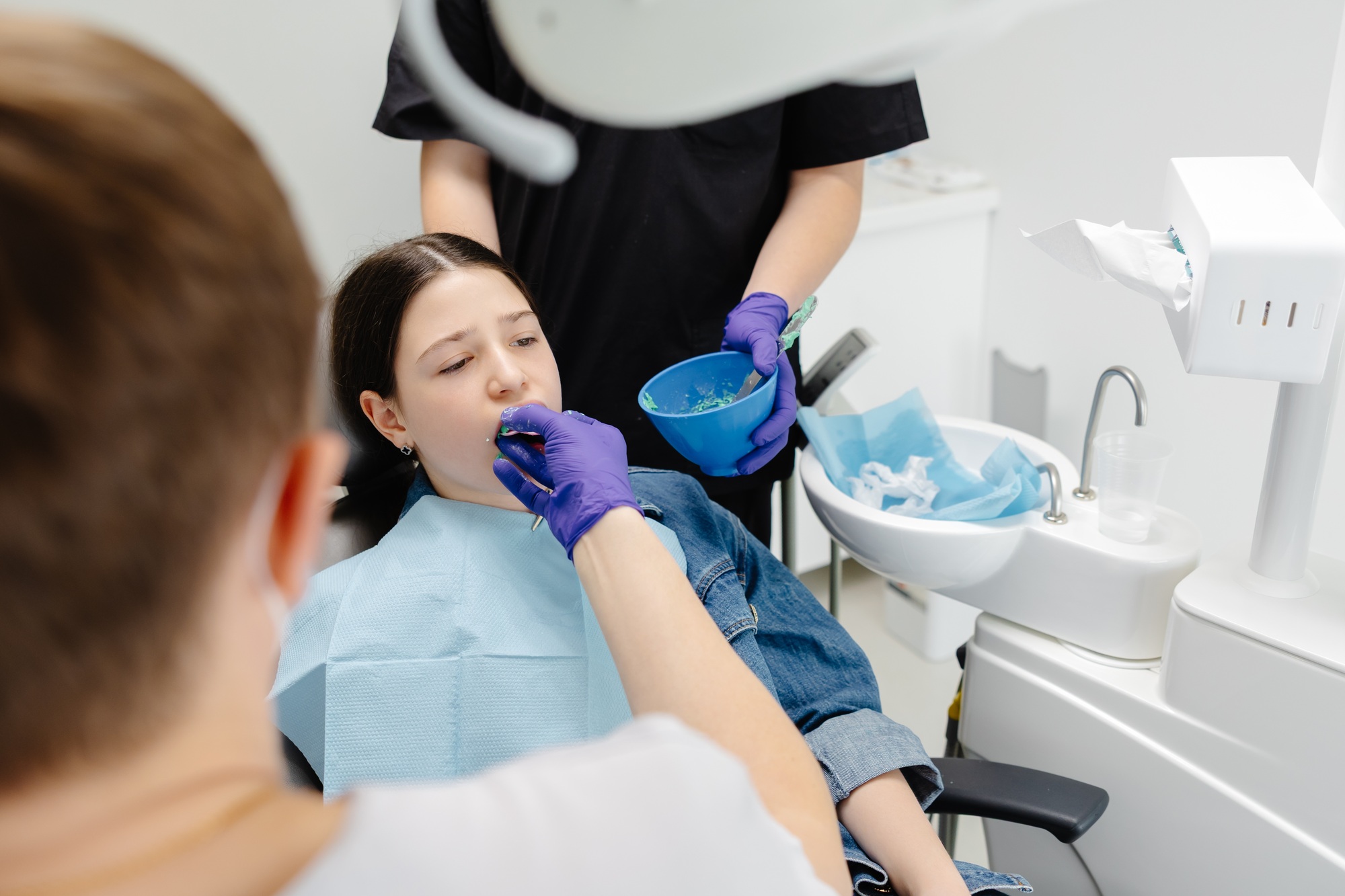 Dentist applying dental sealant on teeth of teenage girl