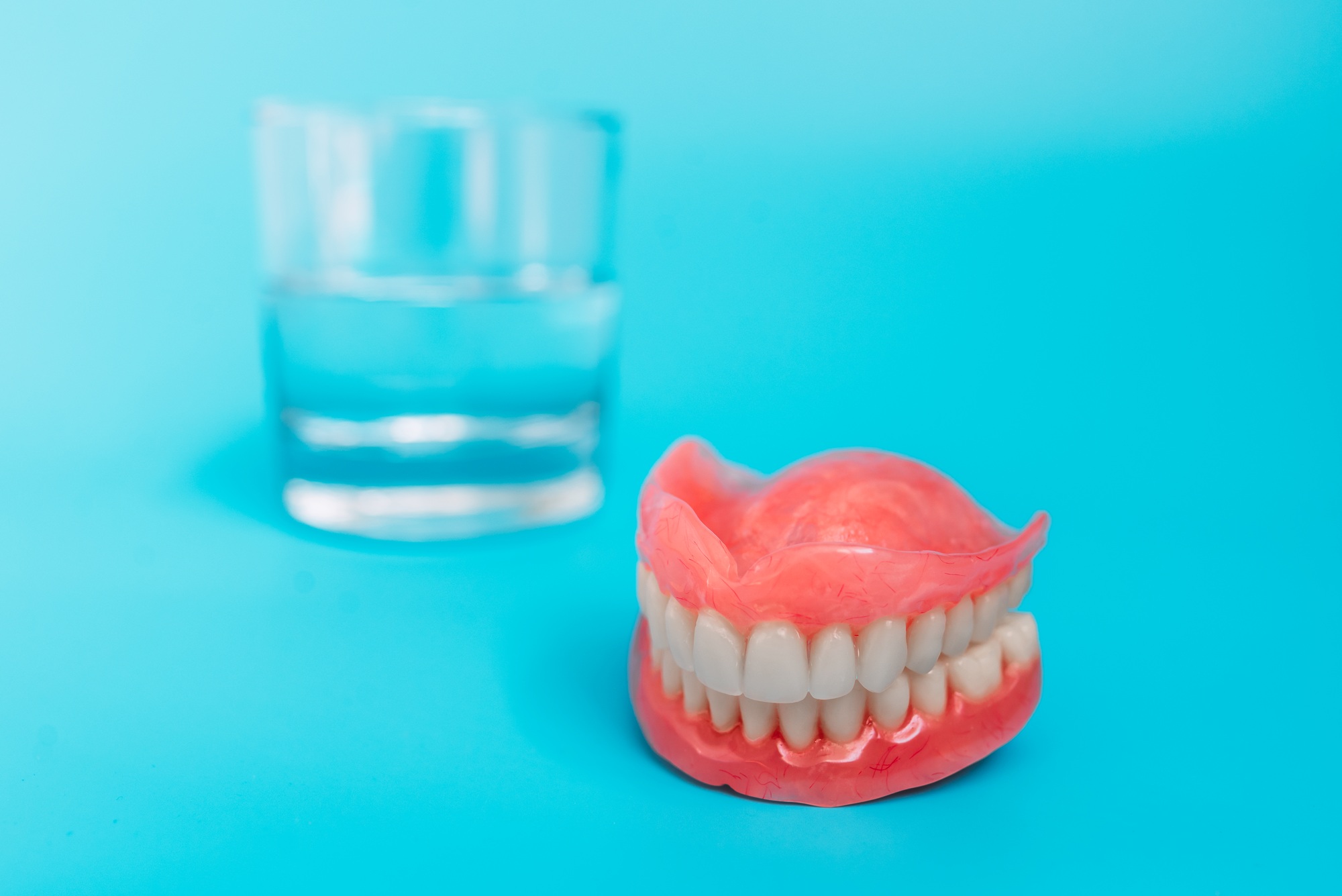 Dentures on a blue background. Close-up of dentures. Full removable plastic denture of the jaws
